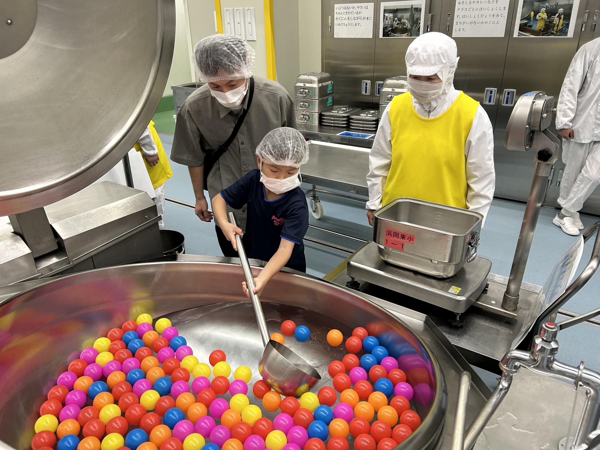 はかりに載せた食缶へ汁物を計量している児童